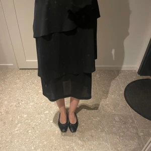 Svart kjol  - Svart kjol med volang. Går en bit nedanför knät på mig som är 170cm 🫶🏻