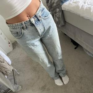 Ljusblå raka jeans från Zara - Säljer ett par klassiska ljusblå jeans från Zara med rak passform och hög/middle midja. Jeansen har fem fickor, knappgylf och är i ett tidlöst denimtyg. Perfekta till vardags och lätta att styla med olika toppar.