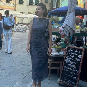 Mörkblå/grön långklänning i mönstrad satin - Säljer en elegant mörkblå långklänning med diskret mönster och ärmlös design. Klänningen har en figurnära passform och rund halsringning. Perfekt för dig som vill ha en stilren och tidlös look.