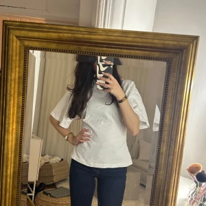 T-shirt med detalj - Jättefin T-shirt med dragkedja baktill som man kan justera så att tröjan får en fin passform. Går att dra upp ända till ringningen i halsen.