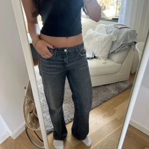 Mörkgrå bootcut jeans - Säljer ett par mörkgrå bootcut jeans med klassisk femficksdesign och låg midja. Jeansen har en lätt tvättad look och raka ben som slutar i en lätt utsvängd form. Perfekta för dig som gillar en avslappnad men ändå trendig stil.
