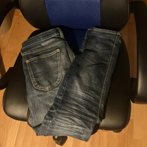 Mörkblå jeans från Lee - Säljer ett par klassiska mörkblå jeans från Lee med snygga slitningar. De är  W 28 och längd 33, slim fit. Inga täcken på användning förutom ett pytte lite hål vid skrevet som inte syns. Priset ej hugget i sten.