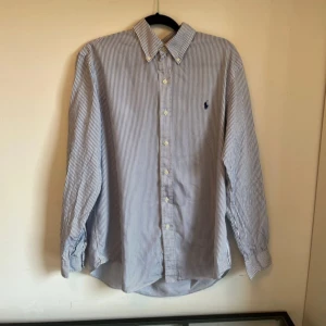 Randig skjorta från Ralph Lauren - Säljer en klassisk blåvit randig skjorta från Ralph Lauren med broderad logga på bröstet. Det är i fint skick, nypris =1600 kr mitt= 350