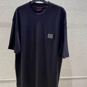 Svart t-shirt från Hugo - Svart t-shirt från Hugo med rund halsringning och en liten logotyp-patch på bröstet. Enkel och stilren design, perfekt för en clean look. T-shirten har normal passform och korta ärmar.