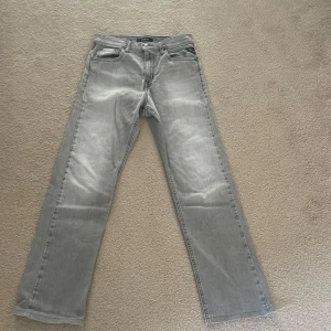 Grå jeansbyxor från Replay - Säljer ett par grå jeansbyxor från Replay med raka ben och klassisk femficksdesign. Byxorna har normal passform och tydliga Replay-detaljer på fickorna. Perfekta för en stilren vardagslook. Modellen är thad, pris 399 är ej hugget i sten.