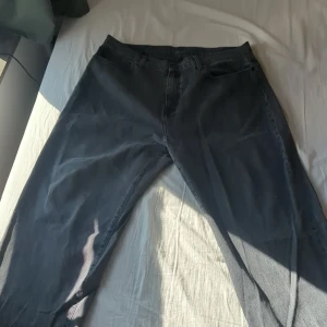 Svarta byxor från Carhartt - Säljer ett par svarta/gråa Landon pant från Carhartt. De har en klassisk design med fem fickor och en bekväm passform. Perfekta för en avslappnad stil.