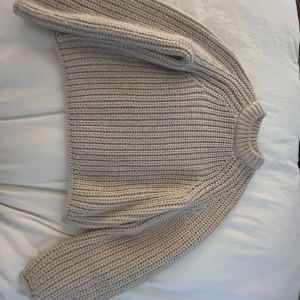 Beige stickad tröja från H&M - Säljer en chunky, beige stickad tröja från H&M i storlek XS. Tröjan har grov ribbstickning, rund hals och långa ärmar. Perfekt för lager-på-lager och en mysig stil under kyliga dagar.