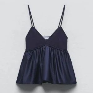 Mörkblått linne - Säljer ett mörkblått linne i satin med dubbla tunna axelband och v-ringning. Toppen har en lös passform och glansigt material som ger en lyxig känsla. Perfekt att styla till jeans eller kjol.