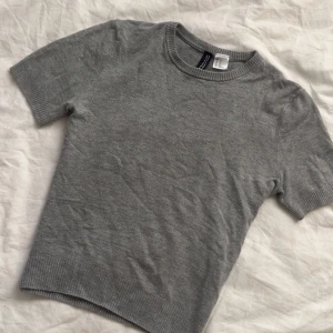 Grå kortärmad tröja från Uniqlo - Säljer en stilren grå tröja från Uniqlo. Den är kortärmad och har en rund halsringning. Perfekt för en avslappnad look. Passar bra till både jeans och kjol.