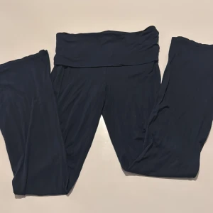 Mörkblå yoga pants från 157 - Mörkblå yoga pants från 157 med bred midjeresår och bootcut ben. Byxorna är tillverkade i ett mjukt och stretchigt material, perfekta för en avslappnad stil. Passar dig som gillar bekväma och enkla plagg.