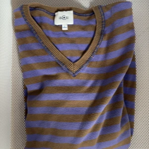 Cerruti tröja - Säljer en randig tröja från 18CRR81 i brunt och lila. Tröjan har en v-ringad hals och är perfekt för en avslappnad stil. Den är tillverkad i ett mjukt material som känns skönt mot huden.