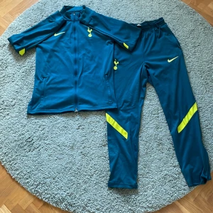 Tottenham Träningsställ  - Säljer ett grönt  Tottenham träningsset från Nike i Dri-Fit material. Setet består av en jacka med dragkedja och byxor, båda med gula detaljer och klubbens logga på bröstet. Perfekt för dig som vill träna i stil och i sköna grejer
