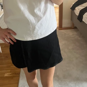 Svart kortkjol från Zara - Säljer en svart byxkjol från Zara med elastisk midja. Kjolen har en enkel design och är lätt att matcha med olika toppar. Perfekt för dig som gillar en stilren och basic look.