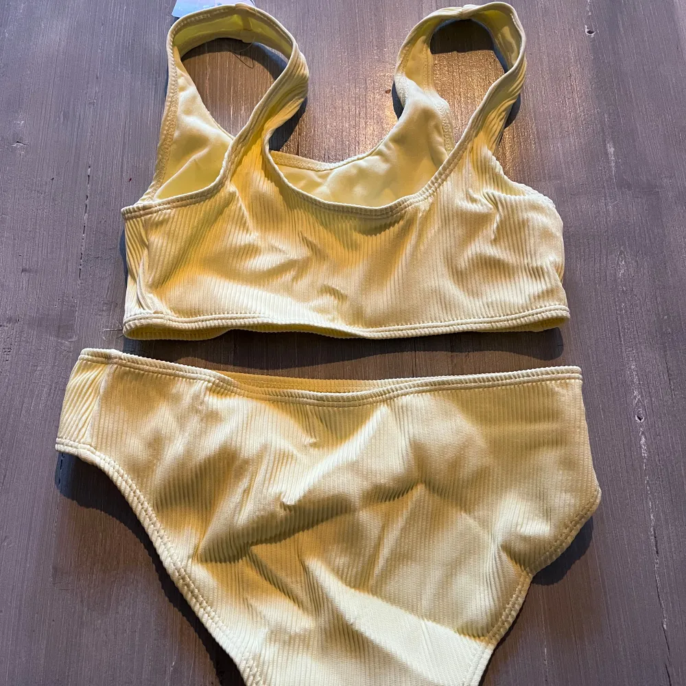 HELT NY och oanvänd gul bikini från KappAhl med ribbad textur. Toppen har breda axelband och en sportig look. Strl 146/152. Nypris: 298 kr, nu 95kr!. Muu.