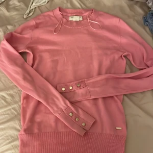 Rosa tröja från Holly & Whyte - Säljer en söt rosa tröja från Holly & Whyte by Lindex. Tröjan har långa ärmar och dekorativa knappar vid ärmsluten. Perfekt för en stilren och färgglad look.