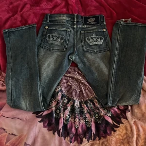 Mörkblå victoria beckham jeansbyxor med broderad krona - Säljer ett par mörkblå jeansbyxor från Victoria Beckham med snygga broderade kronor på bakfickorna. Byxorna passar ganska tight med raka ben och dem är lågmidjade. Perfekta för dig som vill ha ett par jeans med unika detaljer. Säljer då dem är lite små