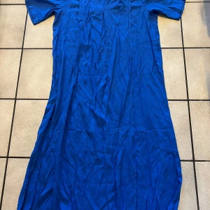 Blå långklänning storlek L/XL - Säljer en stilren blå långklänning med korta ärmar. Perfekt för en avslappnad dag eller en somrig utflykt. Klänningen har en enkel design som gör den lätt att matcha med olika accessoarer.