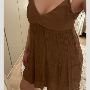 Brun kort klänning  - Supersöt brun kortklänning med v-ringning och smala axelband. 