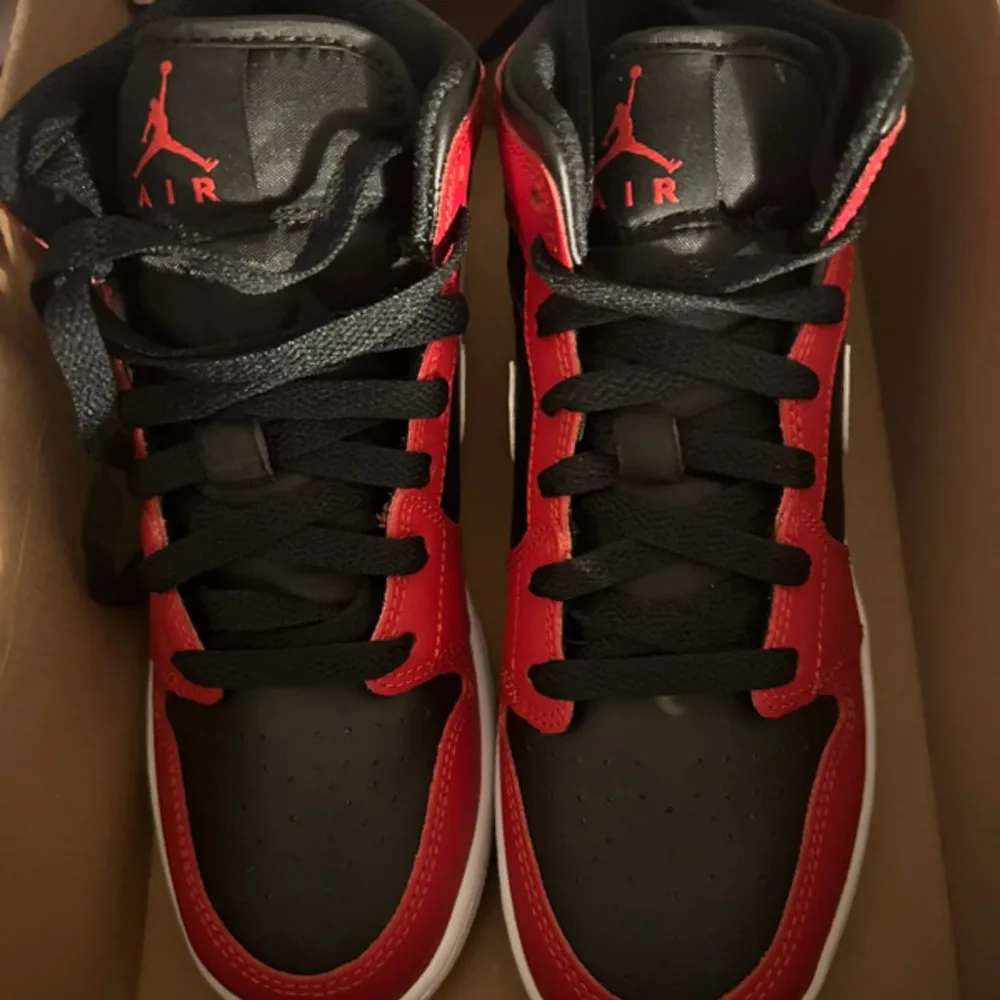 Säljer ett par klassiska Nike Air Jordans med svart bas, röda paneler och vita detaljer. Skorna har vit swoosh, svart snörning och röd Air Jordan-logga. Perfekta för dig som gillar streetstyle och sneakers med ikonisk design.. Kengät.
