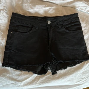 Svarta jeansshorts från H&M - Svarta lågmidjade jeansshorts från H&M med klassisk femficksdesign. Shortsen har normal passform och är tillverkade i bomull. Perfekta för varma dagar och enkel att matcha med olika toppar. Passar för både barn och tonåringar.