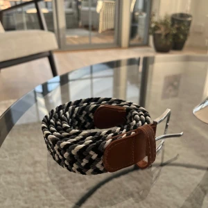 Svartvitt flätat bälte - Tja Säljer ett snyggt svartvitt flätat bälte med bruna skinn-detaljer vid spännet. Bältet är köpt på Kidsbrandstore och använt ett fåtal gånger. Nypris 349kr. Vid minsta lilla fundering tveka inte på att höra av er!
