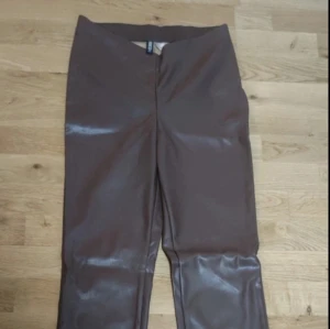 Bruna skinnbyxor med hög midja - Säljer ett par bruna skinnbyxor med hög midja. Byxorna har en rak passform och stängs med dragkedja framtill. Snygga att styla till olika outfits och ger en cool look.