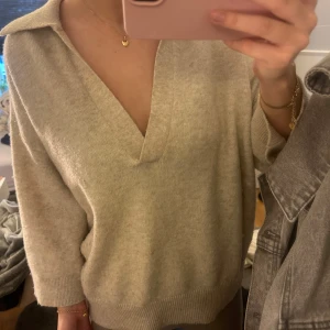 Beige tröja med krage - Säljer en  beige tröja med krage och v-ringning. Tröjan har trekvartsärmar och ribbade muddar vid ärmslut och nederkant. Jätte skön och söt! 