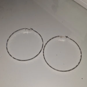 Stora silverfärgade hoops örhängen - Säljer ett par stora, runda hoops i silverfärg med glittrig yta. Perfekta för att ge din look lite extra bling! Lätta att bära och passar till många olika stilar🩷