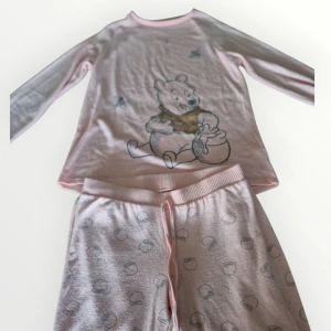 Nalle Puh Pyjamas strl S - En supermjuk och gosig pyjamas med tröja och byxor från Disneys Nalle Puh. Inköpt på Primark. OBS! Finns fläck på tröjan, ser ut att vara från en penna. Har ej prövat att ta bort.