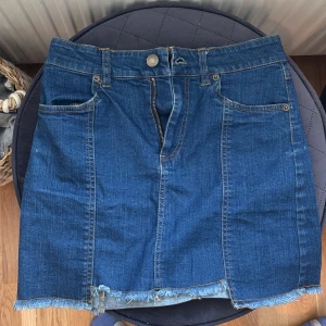 Jeanskjol med fransig kant Forever 21 - Mörkblå jeanskjol från Forever 21 i klassisk modell med fem fickor. Jättefin till sommaren. 