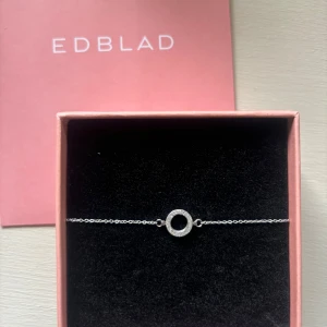 Silverarmband från Edblad med cirkel - Stilrent armband från Edblad i silverfärg med tunn kedja och en glittrig cirkelformad detalj i mitten. Justerbar längd med karbinlås och liten rund Edblad-tag vid låset.💞