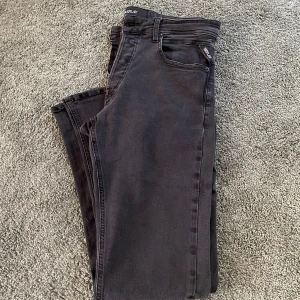 Svarta Replay Grover jeans - Säljer ett par svarta Replay Grover jeans med klassisk femficksdesign och snygga detaljer på bakfickan. Jeansen har en rak passform och är tillverkade i mjukt denimtyg med stretch för extra komfort. Perfekta för dig som gillar stilrena jeans.