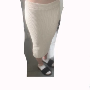 Vit ribbad mellan lång kjol från Gina Tricot - Supersnygg vit ribbad mellan lång kjol från Gina Tricot. Kjolen är figurnära och har en elastisk midja som sitter bekvämt. Perfekt till sneakers eller sandaler för stranden eller sommarens varma dagar. Materialet är stickat och känns mjukt mot huden. Kjolen har några trådar som sticker ut från kjolen, men dem är väldigt enkla att bara klippa bort. Använd ett fåtal gånger förra sommaren. Det står storlek XS men jag har vanligtsvis storlek S men denna passar mig ändå. Jag är 170 cm lång.