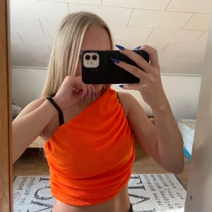 Orange oneshoulder croppad topp - Säljer en snygg orange croppad oneshoulder topp. Använd 1 gång, vet tyvärr inte vilket märke den är ifrån🧡