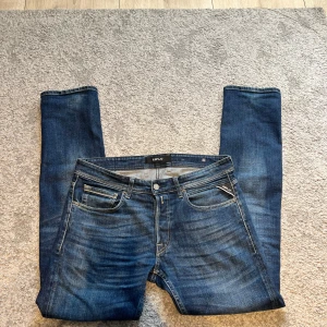 Blå jeans från Replay med raka ben - Snygga blå jeans från Replay med klassisk femficksdesign och raka ben. Jeansen har tydliga slitningar och kontrastsömmar, samt Replay-logga på fickan och läderpatch bak. Perfekta för en avslappnad och cool look.w32 och L34 och är i mycket bra skick.Priset kan diskuteras vid snabb affär 