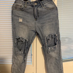 Ljusblå ripped jeans med stora hål - Ljusblå ripped jeans med hög midja i storlek S. Byxorna har råa kanter nedtill. Jag är 157cm och byxorna kommer ovanför min ankel