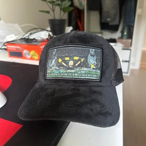 Svart keps med AIK-tryck och mesh - Svart keps med böjd skärm och mesh baktill för extra ventilation. Framsidan har en stor patch med AIK-motiv och texten 'Ta Vakt Om Vår Framtid'. Justerbar snapback baktill. Perfekt för dig som vill visa ditt AIK-stöd på läktaren. Säljer två styckna AIK kepsar som ni kan se på min andra bild!