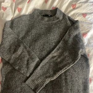 Grå stickad tröja från 157 - Mysig grå stickad tröja från 157 i storlek M. Tröjan har en klassisk rund halsringning och långa ärmar. Perfekt för lager-på-lager och chill dagar. Enkel att matcha med jeans eller kjol för en avslappnad look. Bra skick något nopprig men inget som märks!