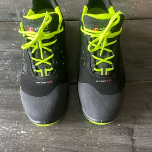 Sixton Peak arbetsskor  - Oanvända svarta arbetsskor från Sixton Peak med neongula detaljer och snörning. Skorna har ventilerande meshfoder, robust PU sula som skyddar mot spik/vassa föremål och aluminiumtåhätta. 