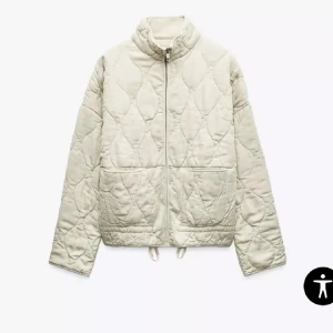 Beige quiltad jacka med dragkedja - Snygg beige quiltad jacka med dragkedja framtill och snörning i nederkant. Jackan har en avslappnad passform och stora fickor framtill. Perfekt för lager-på-lager och ger en cool vibe till din outfit. Storlek xs!🙌🏻