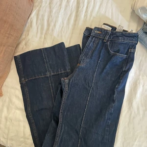 Mörkblå wide jeans från Zara - Säljer ett par mörkblå jeans från Zara med breda ben och hög midja. Jeansen har klassiska fickor, synliga sömmar och är tillverkade i kraftig denim. Perfekta för en trendig och avslappnad look.