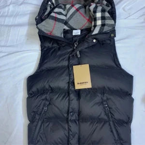 Svart dunväst från Burberry - Fet burberry väst som passar perfekt inför sommaren som passar nästan till allt, håller dig varm när kvällen börjar närma sig. (Pris kan diskuteras) (utan armar)