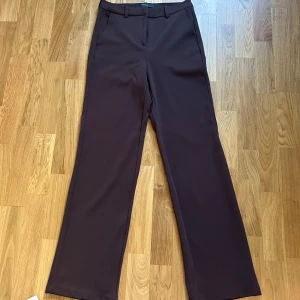 Bruna kostymbyxor från Vero Moda - Snygga bruna kostymbyxor från Vero Moda i rak modell. Byxorna har hög midja, hällor för bälte och klassiska sidfickor. Perfekta för en clean och stilren look, passar till både sneakers och boots. Storlek S💞