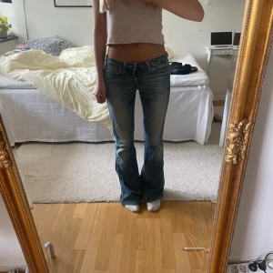 Blå bootcut jeans - Snygga blå bootcut jeans från Sofia med klassisk femficksdesign och låg midja. Jeansen har en lätt tvättad look och är tillverkade i bomull med en skön passform. Perfekta för dig som gillar en avslappnad men trendig stil.