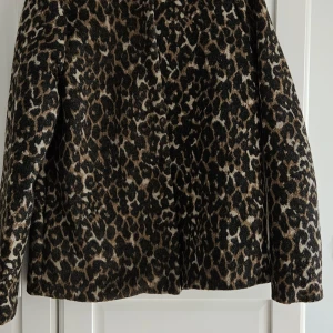 Leopardmönstrad jacka från ICHI - Snygg jacka från ICHI i leopardmönster med bruna, svarta och beige toner. Mörkare i verkligheten. Jackan Lång ärm och klassisk rak passform. Perfekt för dig som vill sticka ut med ett djurmönstrat statement-plagg. Aldrig använd. Står 34 passar 36