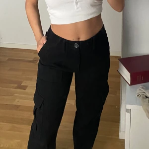 Svarta cargo byxor - Svarta cargo byxor med fickor. Knappt använd men sitter väldigt fint vid midjan.