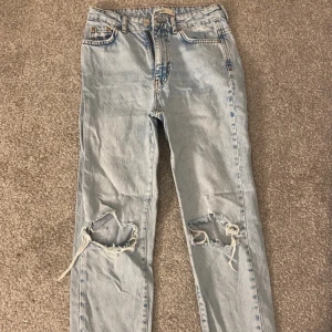 Blåa jeans - 90s jeans med hål på knäna, två olika färger. Stl 32 i fint skick. Båda för 80kr, ett par för 50kr