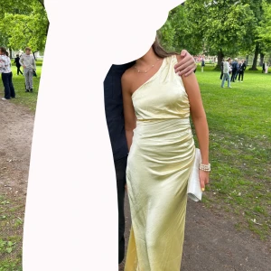 Ljusgul långklänning i satin - Säljer en elegant ljusgul långklänning i satin med oneshoulder-design. Nypris är 1839kr och jag säljer den för 1500kr💛 