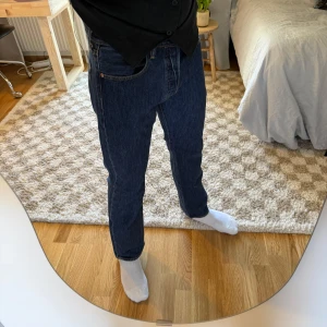Levi's 501 jeans W31 L30 - Klassiska Levi's 501 jeans i mörkblå denim. Rak passform med fem fickor, knappgylf och snygga kontrastsömmar. Ikonisk läderpatch bak i midjan och röd Levi's-tagg på bakfickan.