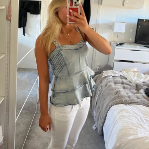 Topp - Bandlös topp i jeanstyg med volanger. 
